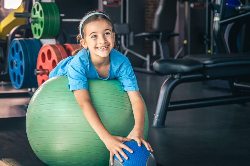 Happy girl stretches her body on a fitball in the gym.