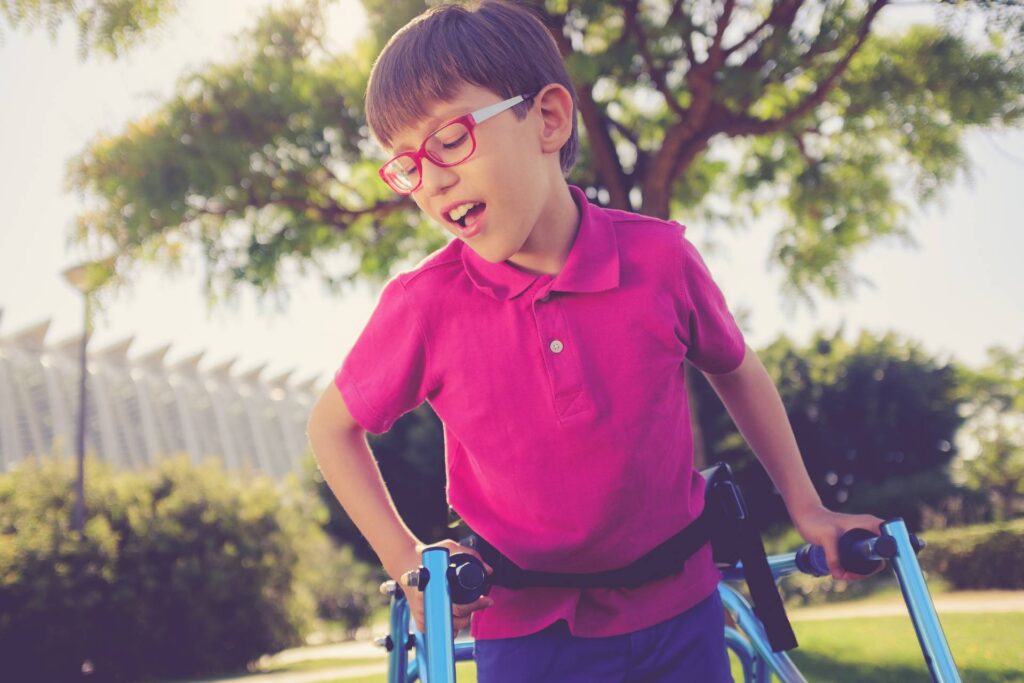 Child walking in a sunny park using walking frame